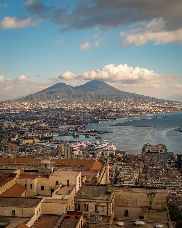 an aerial view of a city with mountains in the back ground and water on the other side