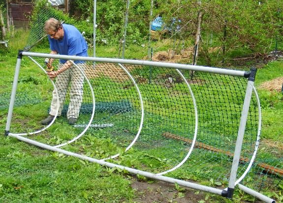 a man is standing in front of a wire fence holding an object with one hand