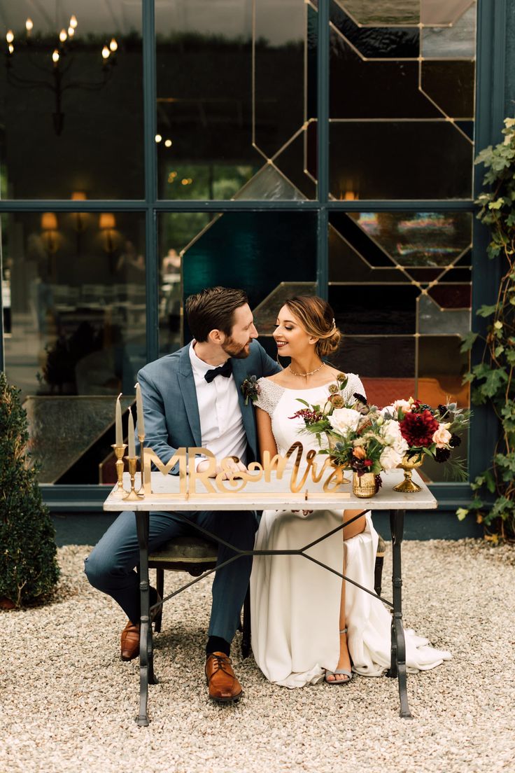 a bride and groom sitting at a table with chess pieces