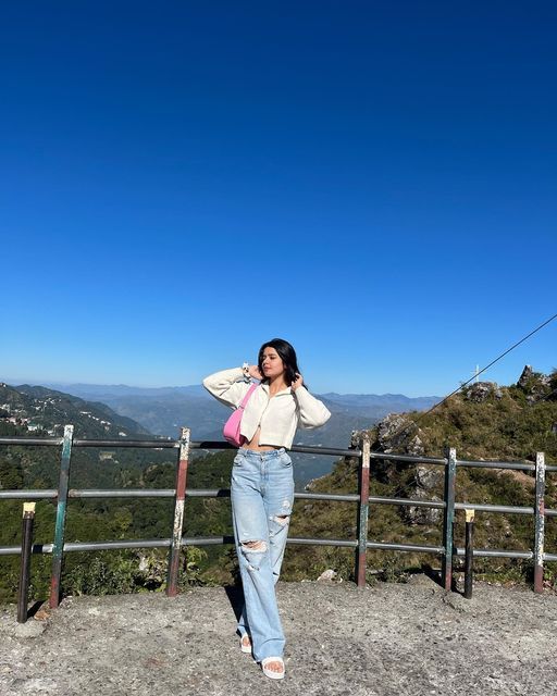 a woman standing on top of a hill next to a fence