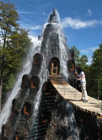 a man standing on top of a wooden bridge next to a water fall in the forest