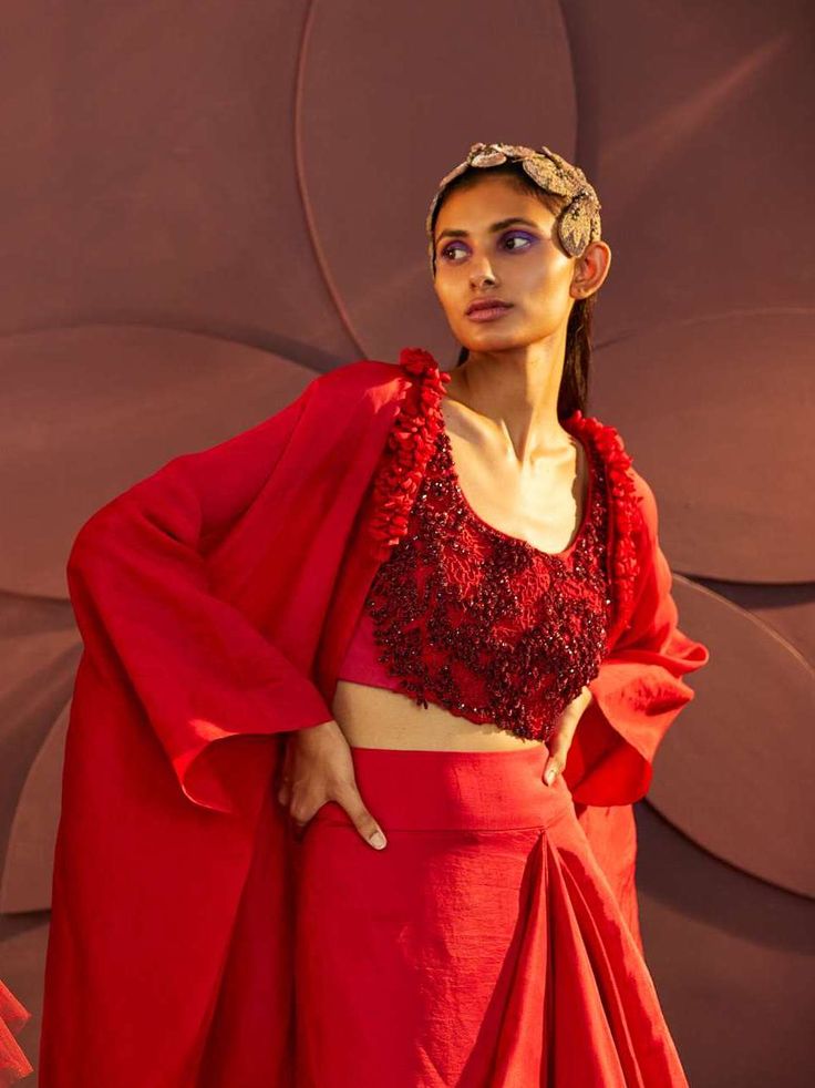 Editor's Note Featuring a cape set matched with drape skirt , embroidered blouse and a cape which carrying hand embroidery and a blouse with an exquisite work of dabka , hand and machoine thread work. Color: Red Fabric: Silk organza, Italian crepe Fit: Fitted Embroidery Details: Dabka & machine thread work Neckline: Scoop Sleeve: blouse: sleeveless, cape: full Component: Skirt, cape, blouse Occasion: Wedding Guest and cocktail Care: Dry clean only Note: Can be customised in any color from design Embroidered Formal Dress With Cape Sleeves, Embroidered Blouse Piece With Cape Sleeves For Wedding, Traditional Blouse With Draped Sleeves, Traditional Silk Sets With Draped Sleeves, Embroidered Draped Blouse Piece For Party, Traditional Georgette Sets With Cape Sleeves, Embroidered Draped Sets For Wedding, Traditional Lehenga With Embroidered Cape Sleeves, Silk Sets With Draped Sleeves