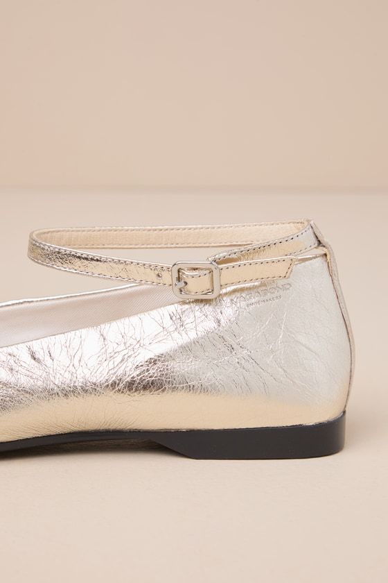 Sweet, chic, and iconic, the Vagabond Delia Gold Metallic Leather Square Toe Ankle Strap Flats are the everyday look we've been dreaming of! Textured, metallic genuine leather shapes these ballet-style flats that have a trendy square toe upper and a low-cut collar. A slender ankle strap sprouts from the heel and secures with a shiny silver buckle, all atop a contrasting black sole. Available in Euro sizes only. 0. 5" rubber heel. Cushioned insole. Rubber sole has nonskid markings. Genuine leathe Chic Gold Leather Ballet Flats, Gold Pointed Toe Ballet Flats For Party, Gold Pointed Toe Ballet Flats For Evening, Gold Leather Ballet Flats For Formal Occasions, Gold Ballet Flats For Formal Occasions, Chic Gold Flats For Parties, Chic Gold Ballet Flats For Evening, Gold Leather Ballet Flats With Round Toe, Gold Leather Ballet Flats With Flat Heel