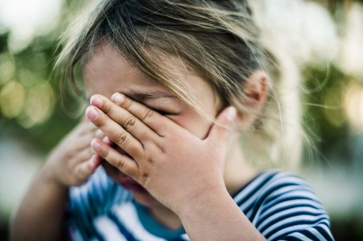 a young boy covering his eyes with his hands