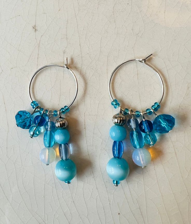 These whimsical, hand crafted, one of a kind earrings are made with silver plated copper wire hoops with aqua blue glass beads and mother of pearl beads.  Assorted beads dangle from the beaded hoops, adding shimmer to the unique earrings.  They sparkle in the sun adding a touch of fun to your look!  All earring hooks are made of high quality material, nickel-free, Hypo-allergenic, safe and durable.  Earrings are approximately 2" long. The beautiful bohemian/hippie style multi-toned earrings woul Blue Dangle Hoop Earrings, Adjustable Blue Hoop Earrings With Dangling Beads, Handmade Blue Round Hoop Earrings, Blue Teardrop Hoop Earrings With Dangling Beads, Handmade Blue Dangle Hoop Earrings, Blue Small Hoop Beaded Earrings With Dangling Beads, Blue Metal Dangle Hoop Earrings, Blue Hypoallergenic Hoop Earrings, Handmade Blue Teardrop Hoop Earrings