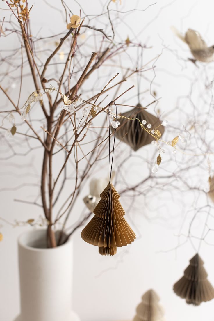 a white vase filled with paper ornaments next to a tree