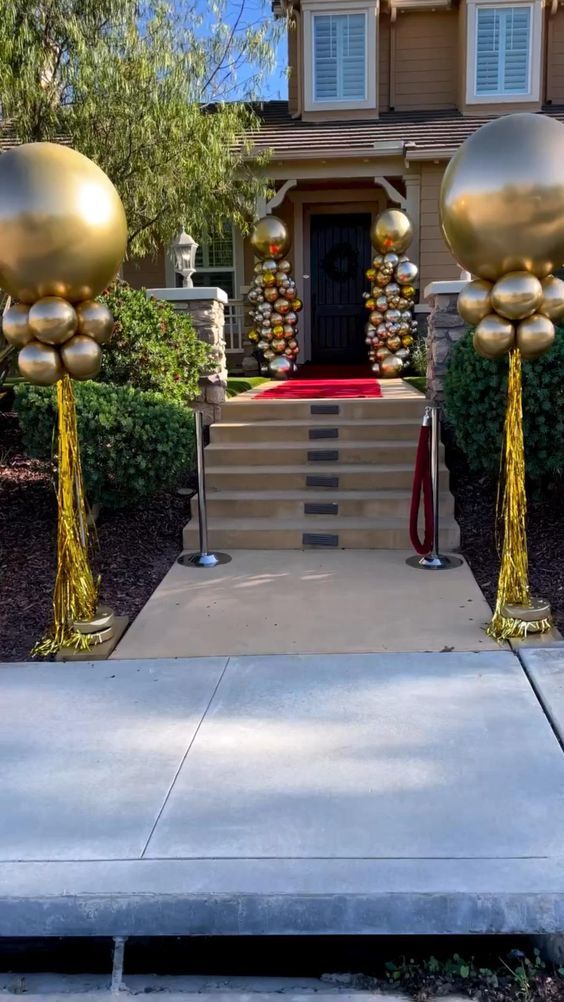 a house decorated for christmas with gold decorations on the front porch and steps leading up to it