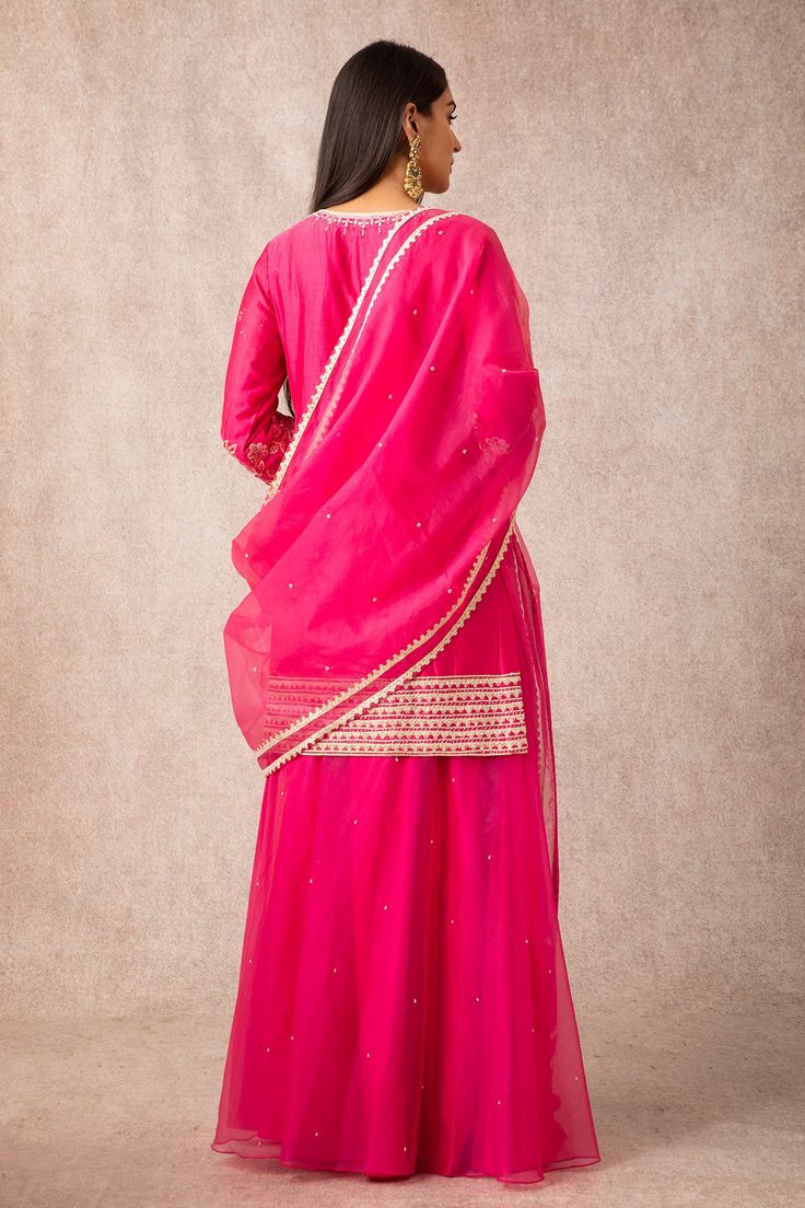 Rani pink straight short kurta with floral motif work and buttoned placket. Comes with gharara pants and organza embroidered dupatta.
Components:3
Embroidered
Neckline:Round
Sleeve Length:Three Quarter
Fabric:Chanderi, Organza
Color:Pink

Side slits
Button front placket
Short kurta
Tassel dupatta - Aza Fashions Pink Chanderi Sharara With Zari Work, Pink Chanderi Palazzo Set With Gota Work, Pink Chanderi Sharara With Sheer Dupatta, Traditional Pink Palazzo Set With Gota Work, Pink Sets With Gota Work For Transitional Season, Festive Unstitched Pink Sharara, Traditional Pink Sharara With Sheer Dupatta, Festive Pink Palazzo Set With Gota Work, Festive Pink Sharara With Sheer Dupatta