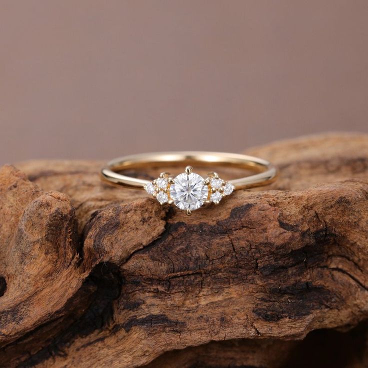 an engagement ring with three stones on top of it sitting on a piece of wood