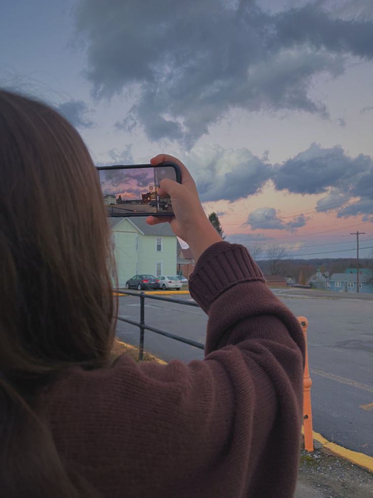 a woman is taking a photo with her cell phone on the side of the road