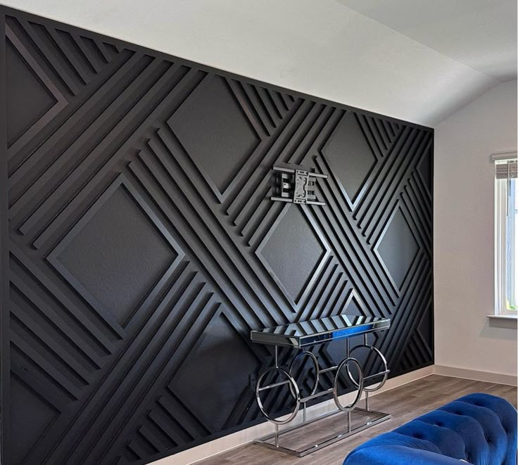 a blue couch sitting in front of a black wall with geometric designs on the walls