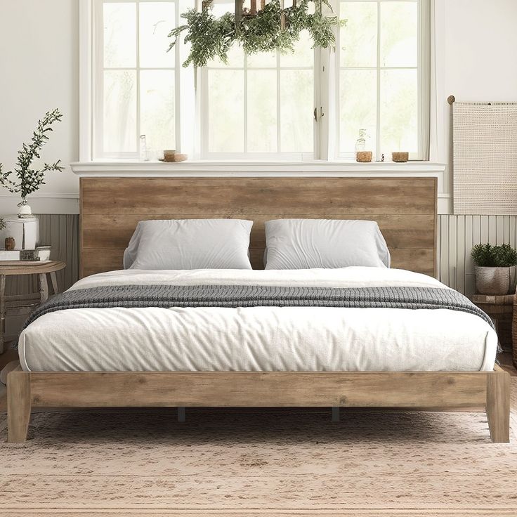 a bed with white sheets and pillows in a room next to a window, potted plants on the wall