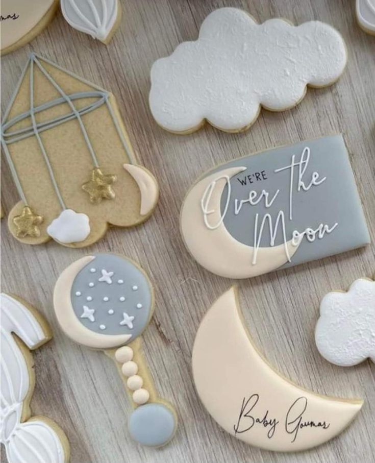 cookies decorated with moon, crescent and stars are arranged on a table next to a sign that says we're the moon