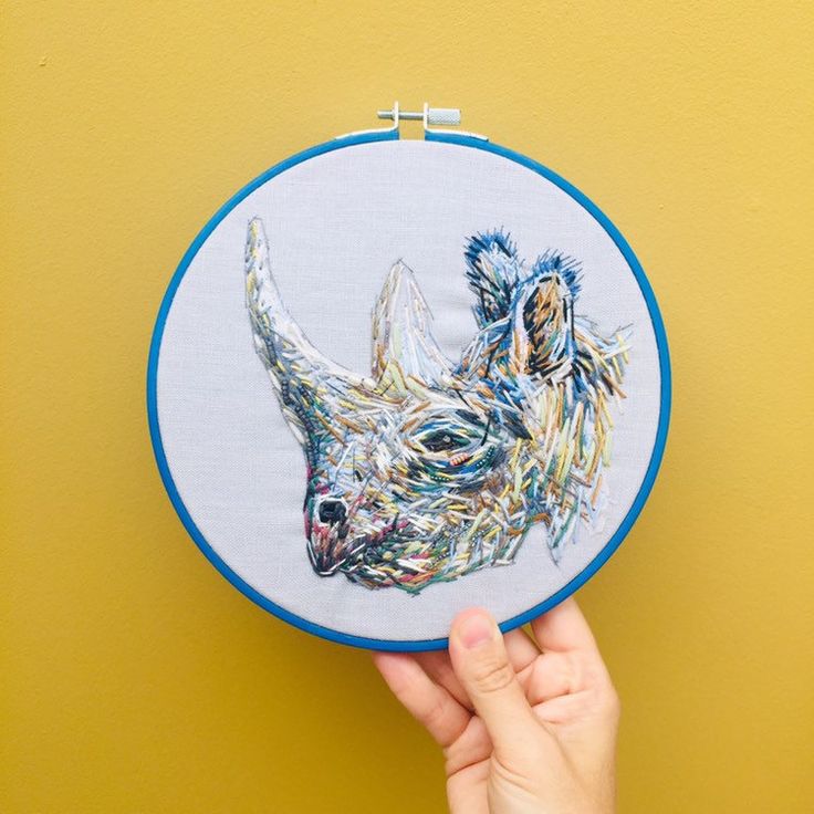 a hand is holding up a small embroidered animal