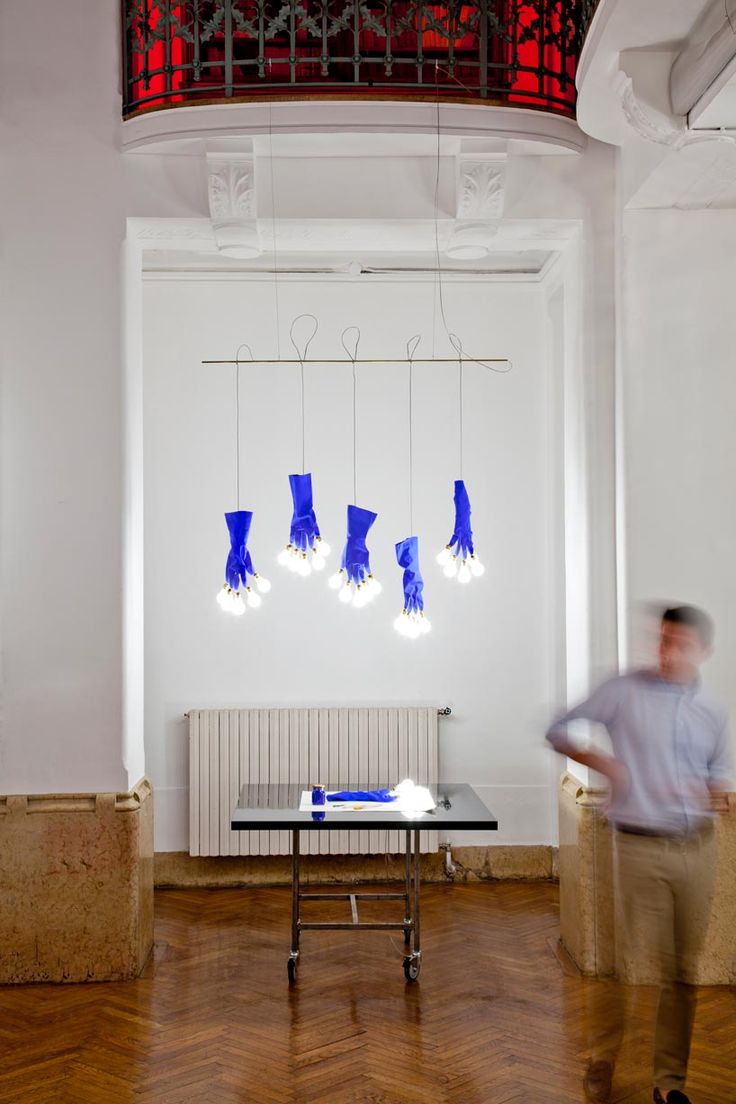 a man standing in front of a table with blue objects hanging from it's ceiling