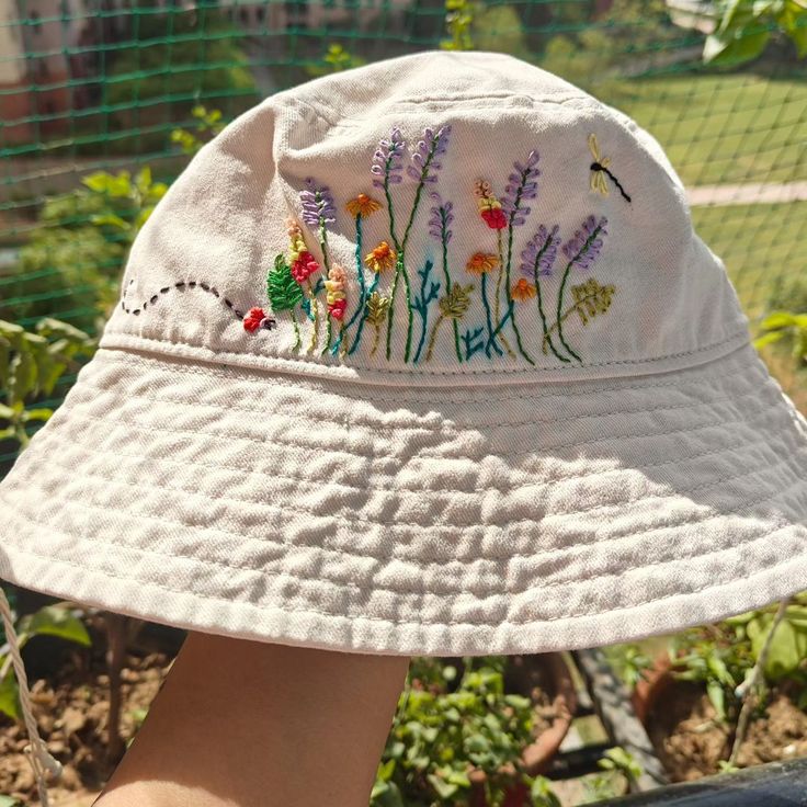 a person wearing a white hat with embroidered flowers on it