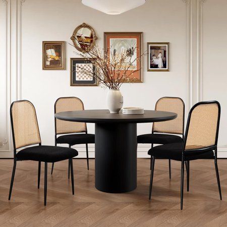 a dining room table with four chairs around it and pictures on the wall behind it