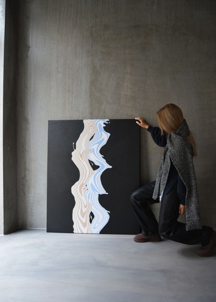 a woman standing next to a large painting