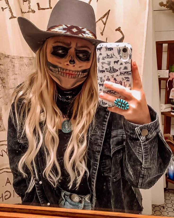 a woman in a cowboy hat taking a selfie with her cell phone