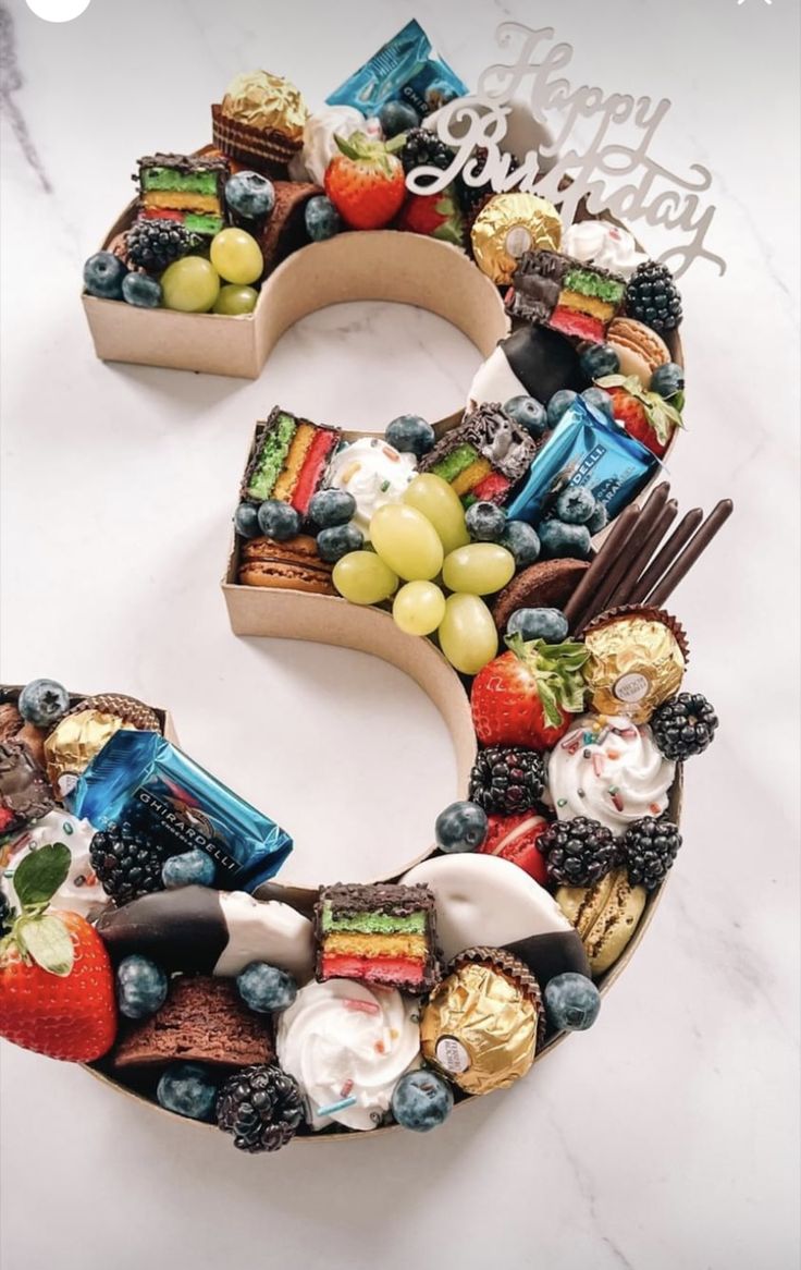 a cake made to look like the letter s with fruit and chocolates on it