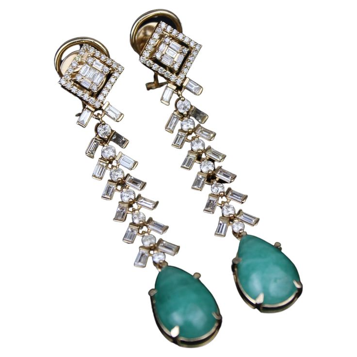 These Tear Drop Emerald Gemstone and Diamond Earrings feature high-quality emerald gemstones set in 18K solid gold and are adorned by baguettes and round diamonds. The elegant dangle drop style adds movement and dimension to the earrings, making them a beautiful and luxurious accessory for any occasion. THE STONES- All our pieces are exquisitely set with the highest quality natural diamonds. These earrings feature round diamonds weighing 1.18 carats and baguette diamonds weighing 1.86 carats. The natural emeralds weigh 8.53 carats (4.25 ct approx each). There is a total of 70 pieces of round, 38 pieces of baguette, and 2 pieces of emeralds. All diamonds are of HI color and SI clarity and are certified and cruelty-free. THE GOLD- All of our designs are set on 100% guaranteed 18k solid gold. Earrings Making, 18k Gold Earrings, Baguette Diamonds, Emerald Gemstone, Baguette Diamond, Natural Emerald, Tear Drop, Exquisite Design, Cruelty Free