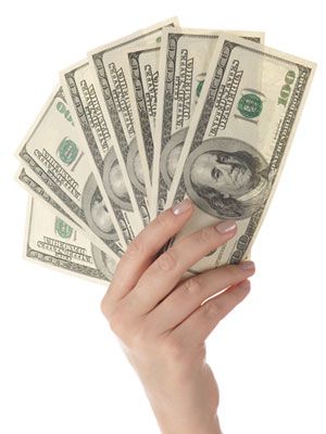 a woman's hand holding five hundred dollar bills in front of her face, on white background