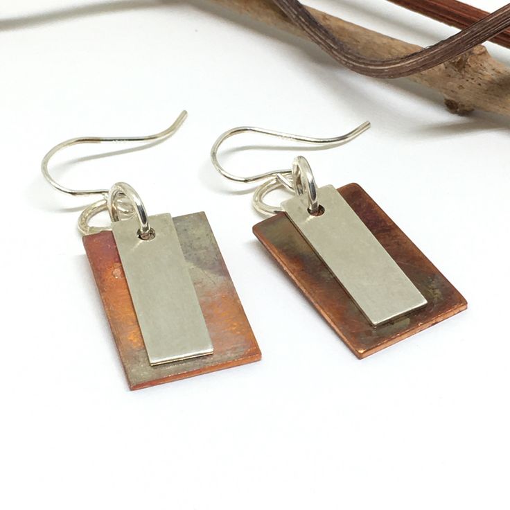 if you are looking to add a special touch to your outfit or need a unique gift, these handmade copper and sterling silver dangle earrings would be perfect. Because of their rich colors and smooth design, these earrings are great to wear to go out with friends or at work, making you feel wonderful and stylish. These earrings are perfect to indulge yourself or as a gift to give joy to someone else for their birthday, graduation, Mother's Day, Christmas, or just to show her some love! The copper on these earrings has been treated with heat bringing unique colors to the rectangle making each one different and allowing the copper not to tarnish, because of this no one earrings will have the same colors. The sterling silver rectangle has been textured. Each piece is handmade by me. The drop leng Rectangular Copper Earrings With Ear Wire, Minimalist Cadmium-free Dangle Earrings, Soldered Copper Earrings As A Gift, Handmade Rectangular Copper Earrings, Artisan Adjustable Earrings As A Gift, Adjustable Artisan Earrings For Gifts, Artisan Adjustable Earrings For Gifts, Unique Copper Earrings For Gift, Unique Copper Earrings As Gift