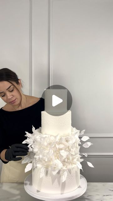 a woman is decorating a white wedding cake