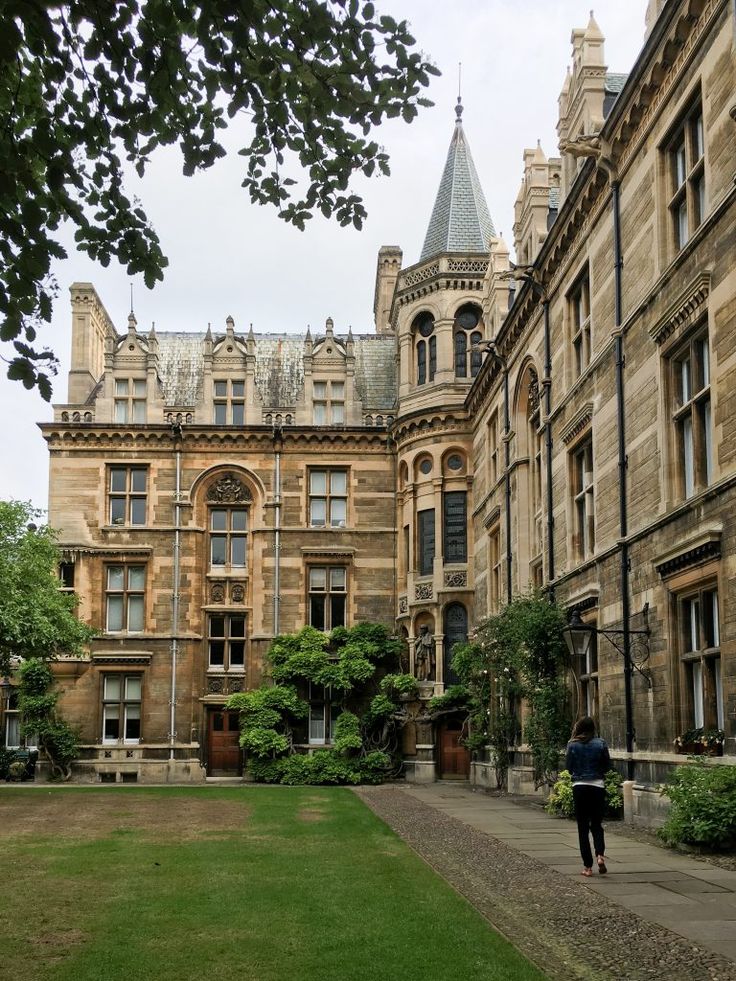 a person walking down a sidewalk in front of an old building with many windows and towers