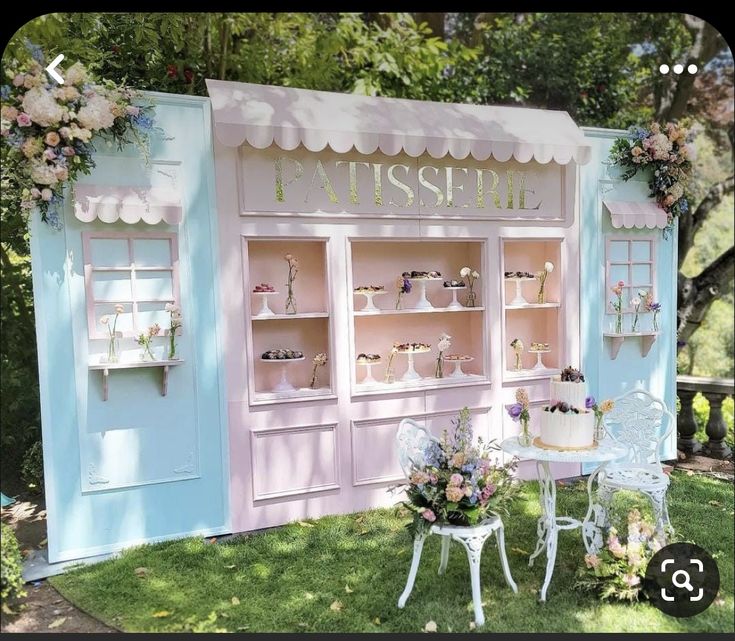 a table and chairs in front of a store with flowers on the outside wall,