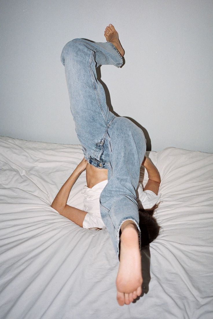 a woman laying on top of a bed with her legs spread out in the air