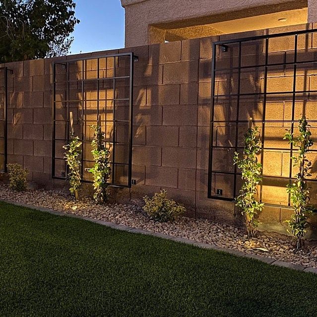 a fence that is next to a building with plants growing on the side of it