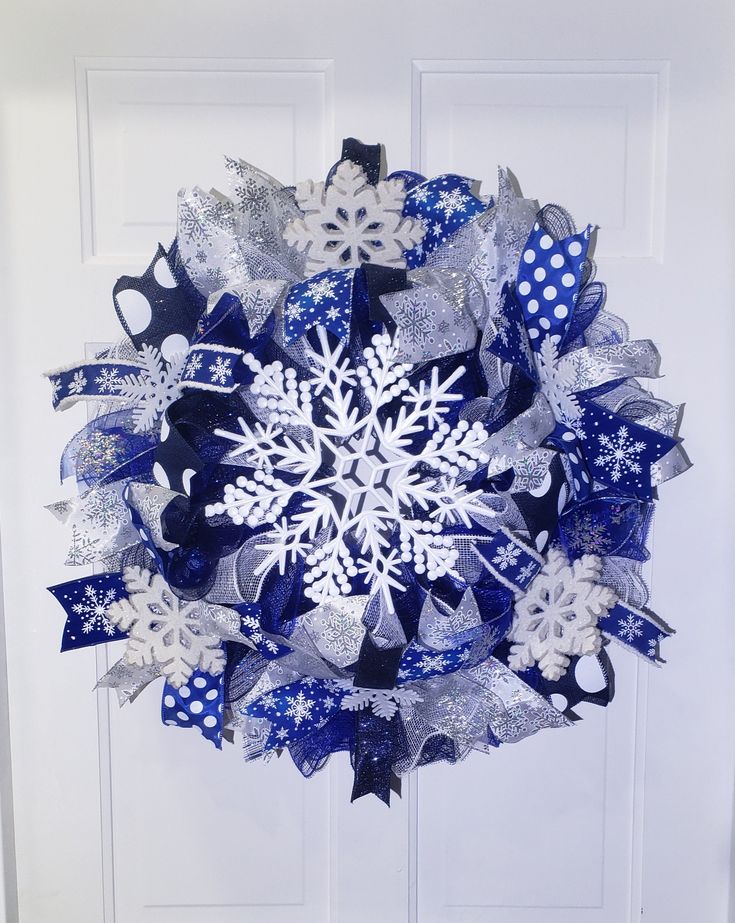 a blue and white christmas wreath with snowflakes hanging on the front door,