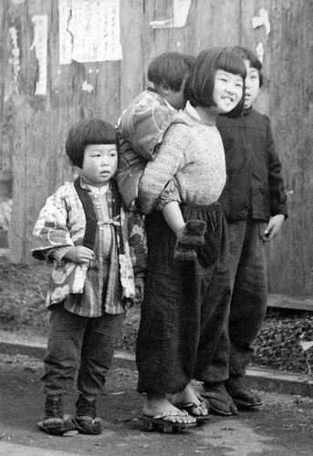 a group of children standing next to each other in front of a wooden fence and building