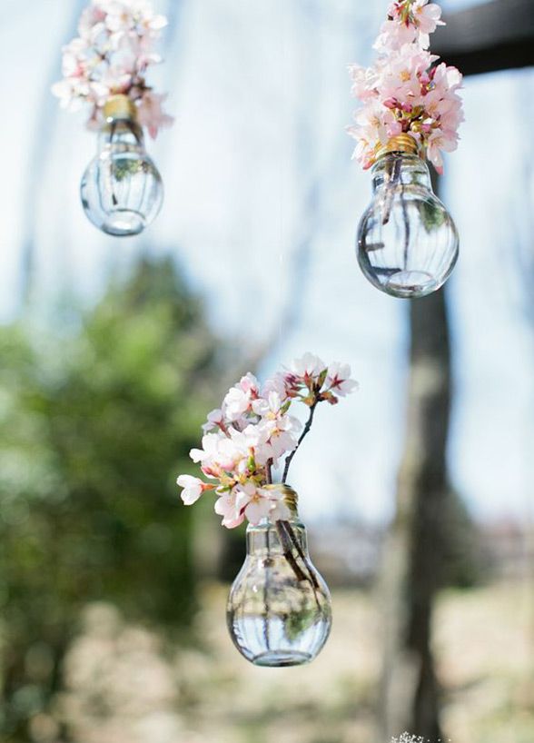 three glass vases with flowers hanging from them