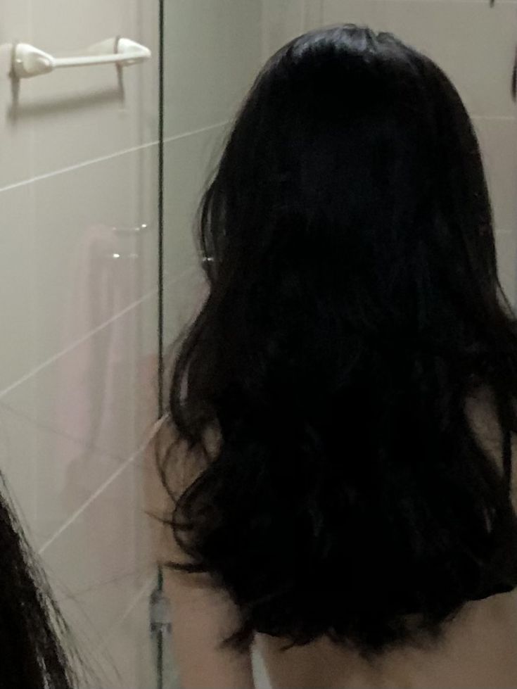 the back of a woman's head in front of a bathroom mirror