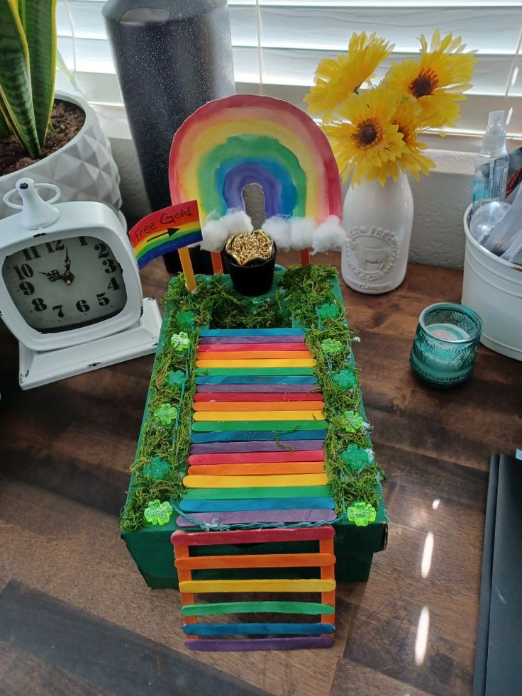 a cake made to look like a rainbow with grass and sunflowers in the background