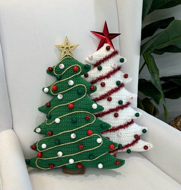 two crocheted christmas trees sitting on top of a white chair