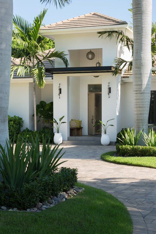 a white house with palm trees in the front yard and walkway leading up to it