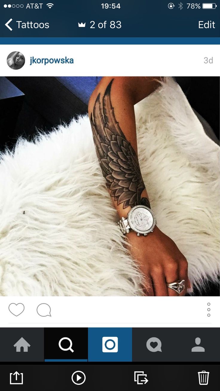 a person with tattoos on their arm and wrist sitting on a white furry rug next to a cell phone