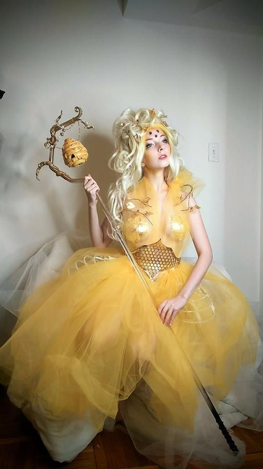 a woman in a yellow dress holding a wand