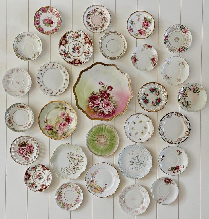 many plates are arranged in the shape of a flowered wall hanging on a white wall