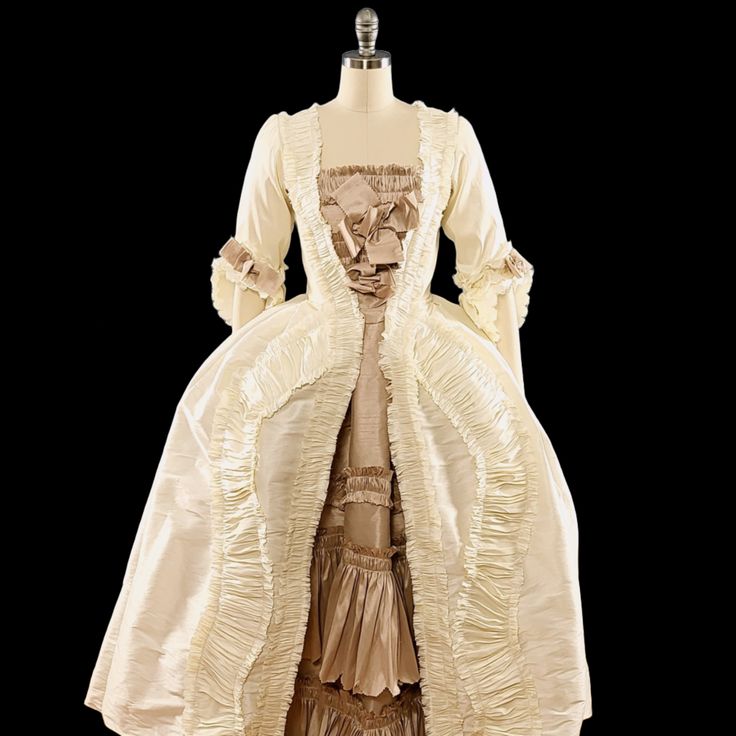 A Rococo Style gown made from polyester dupioni. The gown features an abundance of ruffles, made from the same fabric as the gown and strategically placed to add volume and movement to the dress. The separate underskirt is also decorated with ruffles and will provide additional volume and texture to the overall look of the gown. The sack back drapes elegantly over the back and hips and creates a soft, flowing silhouette.This dress can be made in many different color combinations. The front of th Couture Evening Dress With Ruffles, Rococo Style Ball Gown With Ruffles, Rococo Ball Gown With Ruffles, Elegant Ball Gown With Ruffled Skirt, Taffeta Ball Gown Wedding Dress, Regency Style Cream Dress With Ruffles, Satin Evening Dress With Ruffles And Fitted Bodice, Couture Gown With Ruffles And Fitted Bodice, Satin Ruffled Ball Gown For Evening