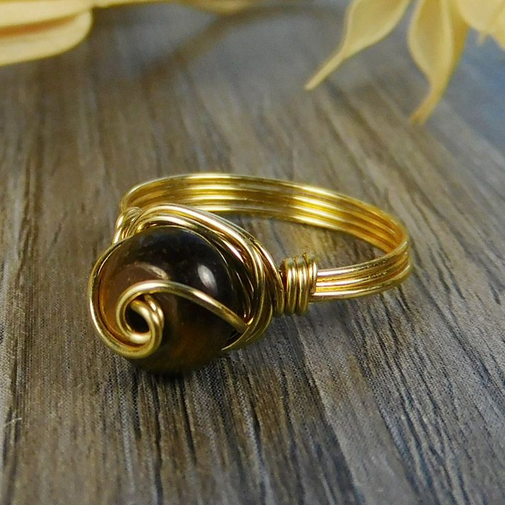 "Golden Tigers Eye Gemstone and Sterling Silver, Yellow or Rose Gold Filled Wire Wrapped Swirl Ring; Custom Made to Size ❀ This round golden tigers eye gemstone bead and wire wrapped ring is handmade with an approximately 8mm by 5mm bead and your choice of wire for the band. ❀ This ring (as well as all the others in my shop) is custom made to any size from 4 to 14 including half and quarter sizes! ❀ This ring can be made in Sterling Silver Filled Wire, Argentium Sterling Silver wire (tarnish res Wire Wrapped Crystal Ring For Anniversary, Spiral Stackable Jewelry For Gifts, Adjustable Brown Ring Jewelry, Spiral Shape Stackable Jewelry Gift, Handmade Spiral Promise Ring, Spiral Stackable Jewelry Gift, Hand Wrapped Round Jewelry For Anniversary, Adjustable Stackable Brown Jewelry, Adjustable Gold Wire Wrapped Rings