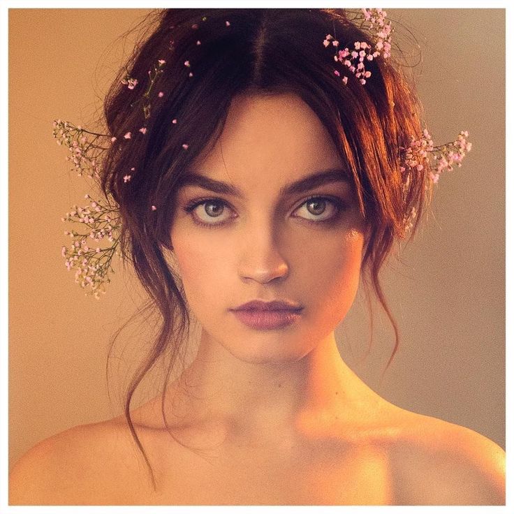 a woman with flowers in her hair and blue eyes is posing for the camera while wearing a dress