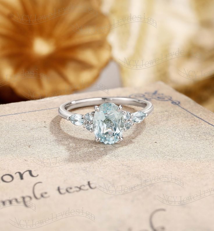 an oval cut aqua blue topazte ring sits on a book