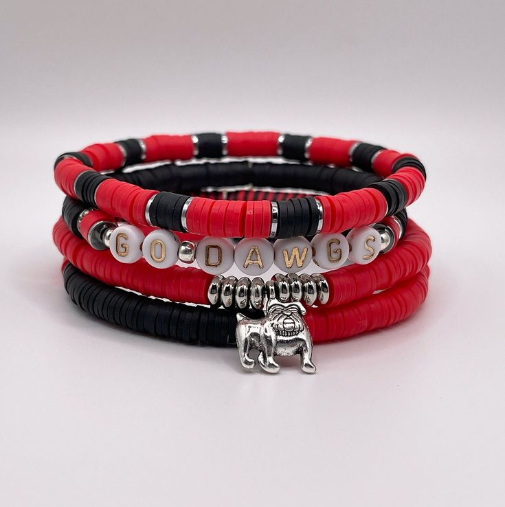 Show your team pride with our set of 4 red and black game day stackable bracelets. Each handmade bracelet is made from polymer clay heishi discs on stretch beading thread and finished with silver plated bulldog or football charm. Georgia Bulldogs Clay Bead Bracelet, Red Stacked Beaded Bracelets For Gifts, Red Stacked Beaded Bracelets As Gift, Red Heishi Beads Jewelry With Letter Beads, Red Heishi Bead Jewelry With Letter Beads, Red Adjustable Stacked Bracelets, Adjustable Stacked Red Bracelets, Adjustable Red Stacked Beaded Bracelets, Adjustable Stacked Red Beaded Bracelets