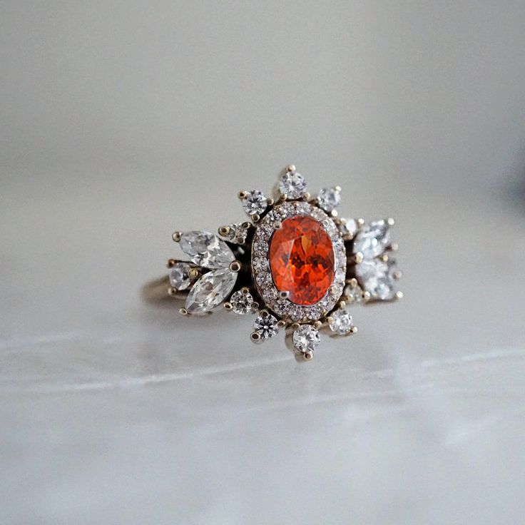 Immerse yourself in a world of timeless beauty with our Coco Fanta Orange Spessartite Garnet Coco Diamond Ring, a true testament to class and elegance. This ring seamlessly combines the grace of marquise and round diamonds, elevating the sense of style on the wearer. A proportionately beautiful design with a touch of vintage charm, it features a natural vivid Orange Spessartite adorned with the brilliance of natural white diamonds. Handcrafted with precision, this ring is available in 14K and 18K yellow gold, rose gold, and white gold. Only one available. Spessartite/Spessartine is known for its fiery red-orange color, hence why it's called the "Garnet of the sun". Spessartine garnet is a stone known for positive emotions and creativity. It encourages a rational state of mind, emotional st Heirloom Orange Jewelry For Anniversary, Orange 14k Gold Wedding Ring, Orange Heirloom Ring In 14k Gold, Heirloom 14k Gold Orange Ring, Heirloom Style 14k Gold Orange Ring, Heirloom Orange Gemstone Ring, Orange Multi-stone Wedding Jewelry, Fanta Orange, Spessartine Garnet