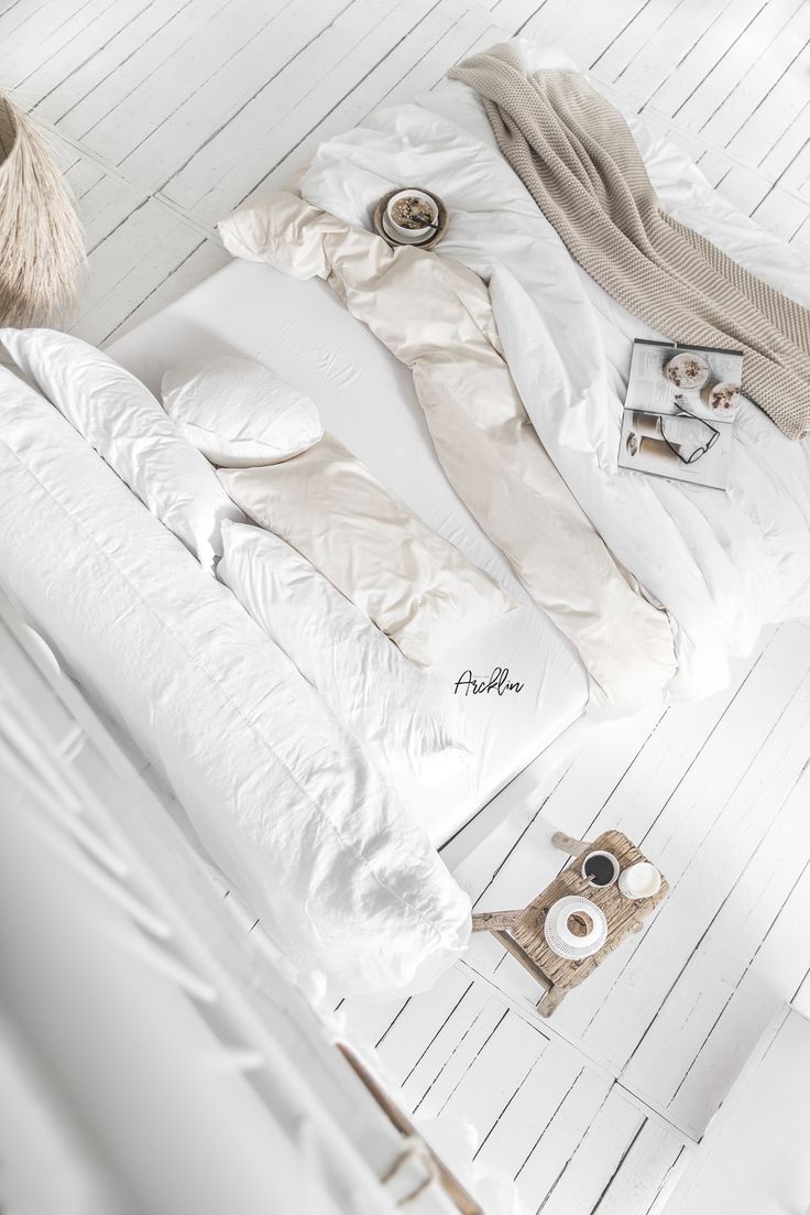 an unmade bed with white sheets and pillows on the floor next to a stuffed animal