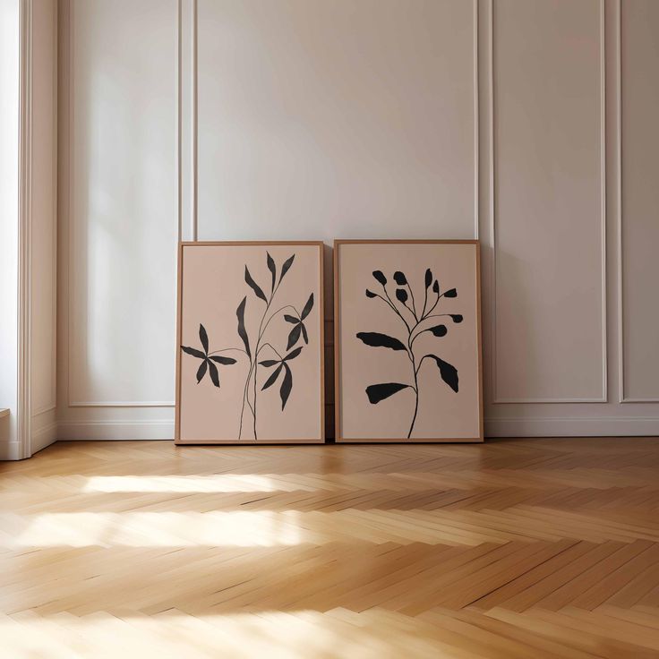 two black and white paintings sitting on top of a wooden floor